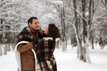 A young couple walk in a winter park