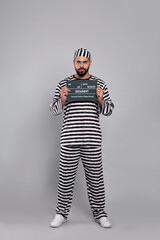 Prisoner in special uniform with mugshot letter board