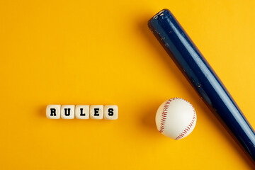 Wooden baseball bat and a ball on yellow background with the word rules.