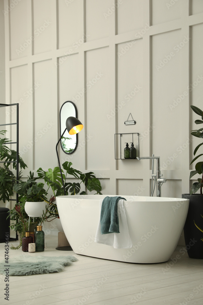 Poster Stylish bathroom interior with modern tub and beautiful houseplants. Home design