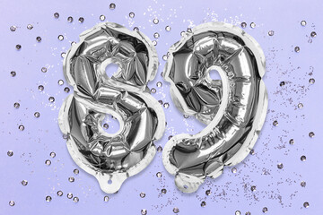 Silver foil balloon number, digit eighty nine on a lilac background with sequins. Birthday greeting card with inscription 89. Top view. Numerical digit. Celebration event, template.