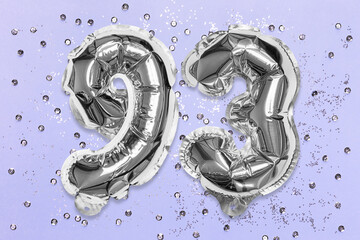 Silver foil balloon number, digit ninety three on a lilac background with sequins. Birthday greeting card with inscription 93. Top view. Numerical digit. Celebration event, template.