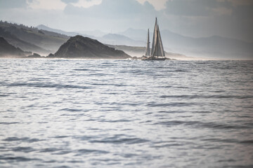 isolated sailing boat cruising on atlantic ocean beside ile des cochons, basque country, france, creative background