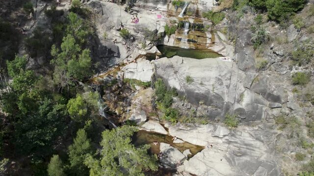Aerial circular view over people sunbathing on rocks, at waterfall Fecha de Barjas. National Park Peneda-Ger&ecirc;s, Portugal