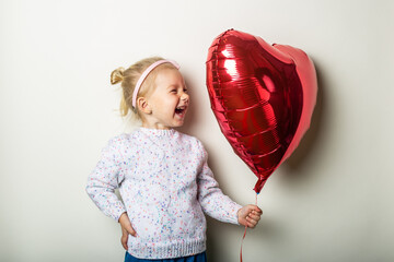 Little girl catches a heart air balloon on a light background. Concept for Valentine's Day, birthday. Banner © Alex
