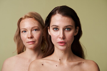 Two diverse women with naked shoulders standing behind of each other