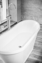 A young, slender, red-haired girl in a black bathroom robe stands in the sunlight through blinds