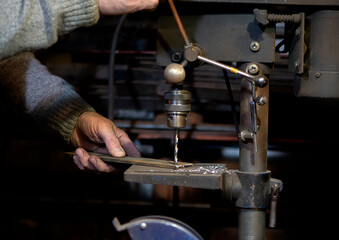 Blacksmith uses drill press in garage. A close up view of a metalworker operating a bench drill...