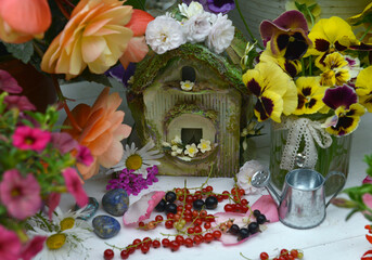 Cute miniature house for dolls with berries and flowers outside in the garden.