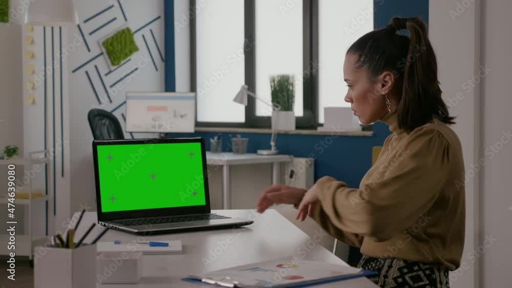 Poster woman sitting at desk with green screen on laptop, working with chroma key template and isolated moc