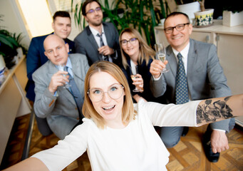 Fototapeta na wymiar Happy business people team with champagne glasses taking selfie at business meeting
