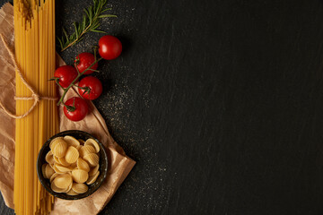 pasta concept some kinds of pasta placed into a paper bag, and some placed on the ground with other ingredients and cooking devices in organized position