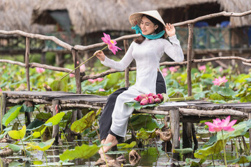 Portrait of beautiful vietnamese woman with traditional vietnam hat holding the pink lotus on the...