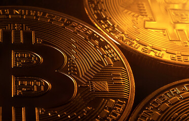 Bitcoin coins on a black background with golden highlights. Cryptocurrency market