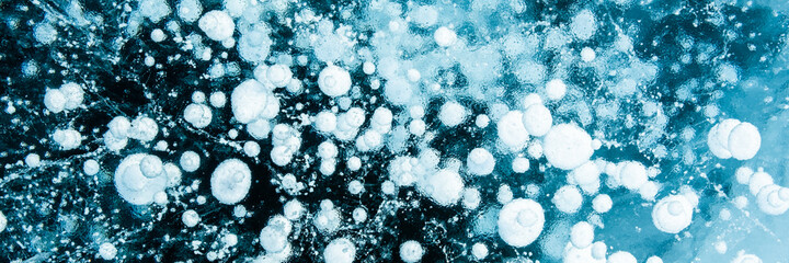 Texture of beautiful blue ice with cracks and air bubbles in the frozen lake. Winter nature...