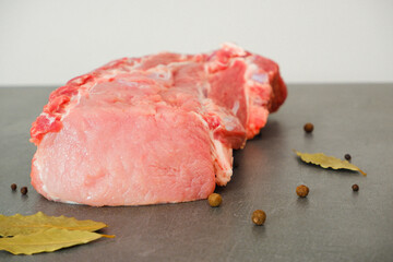 Raw meat. Uncooked fresh pork. A large juicy fresh piece of meat on a gray stone during cooking. Pepper, bay leaf. Culinary concept.