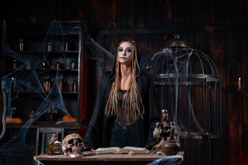 Halloween concept. Witch dressed black hood with dreadlocks standing dark dungeon room use magic...