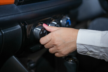 Selective focus, Woman's hand adjusting the cooling level in the car cabin to save energy.