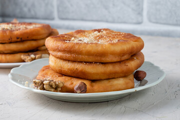 Korean hotteok flatbreads fried in oil stuffed with hazelnuts, sugar and cinnamon. They lie in a plate on a white table.