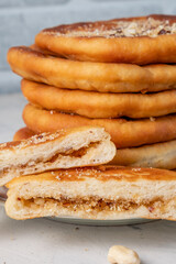 Stack of hotteoks close-up. South Korean dessert stuffed with nuts, sugar and cinnamon. One piece in a cut.