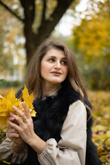 girl model holding yellow leaves in her hand. photo session of the girl in the autumn park. 