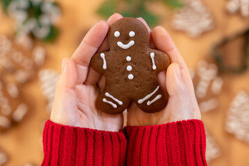 Christmas gingerbreads in the form of a man in the hands of a girl against the background of New Year's decor, close-up, top view