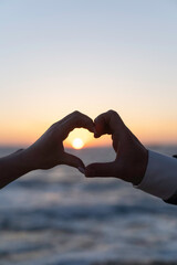 Couple holding hands in a shape of a heart during sunset. Concept of love, relations. - 474645601