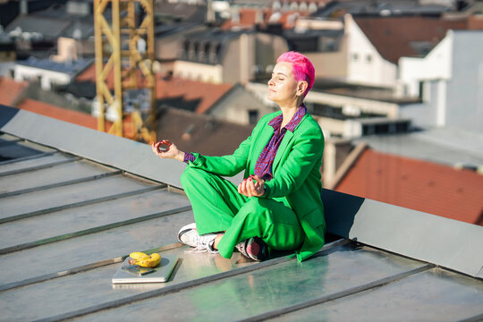 Businesswoman meditating at rooftop on sunny day