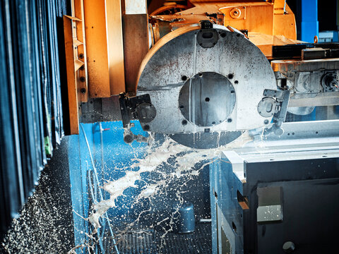 CNC machine splashing water while cutting material inside modern factory