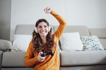 Happy woman with hand raised playing video game at home