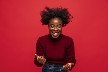 Fototapeta na wymiar Portrait of beautiful cheerful dark skinned young girl laughing isolated on dark red studio background.
