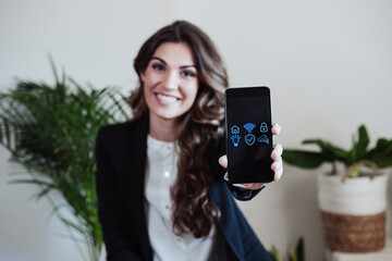 Young businesswoman showing smart phone with home automation software