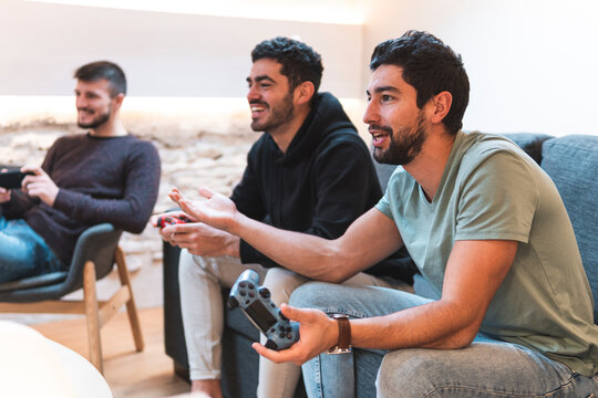 Excited friends playing video game together at home - Powered by Adobe