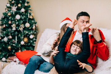 Happy smiling family having fun and fool with kid son. Laughing mother in Santa hat, father, child...