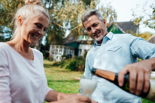 Smiling man pouring champagne in flute for woman at backyard