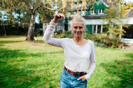 Woman With Hand In Pocket Holding House Key At Backyard