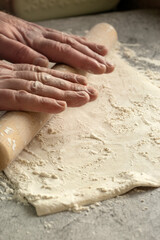 Man rolling out a sheet of puff pastry.  On a concrete surface