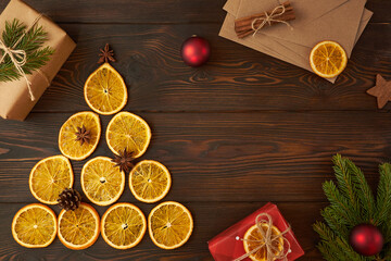 Christmas tree made of dry oranges and envelopes on a dark brown wooden background. Creative festive decoration concept.