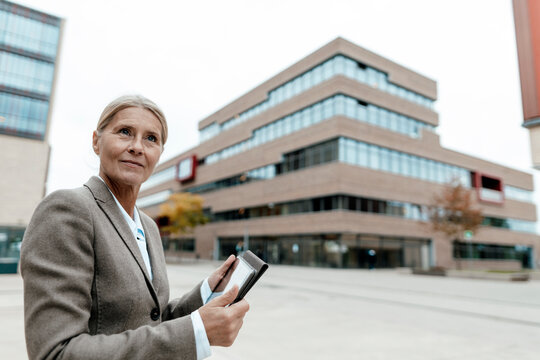 Businesswoman using tablet PC on city street