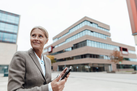 Smiling businesswoman holding tablet PC in city