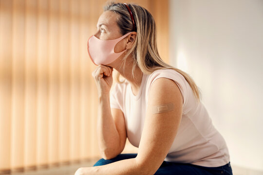 Viral Vaccination And Side Effects. A Woman Sitting In The Hospital With Her Hand Under The Chin After Covid 19 Vaccination And Thinking About Side Effects.