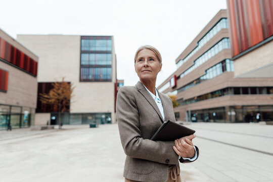 Thoughtful businesswoman with tablet PC at city