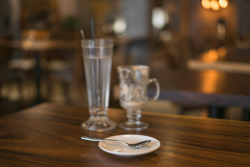 Two empty iced coffee glass cups on the table in coffee shop and white saucer with a spoon. High quality photo