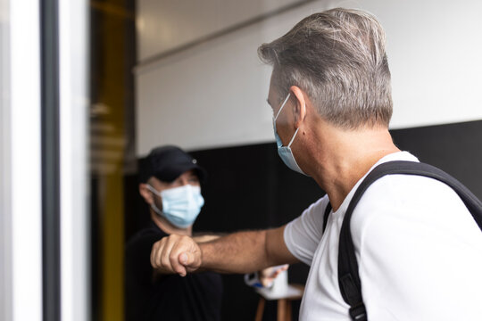 Friends wearing protective face mask doing elbow bump in gym