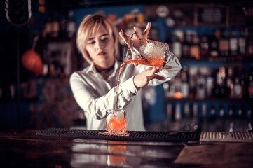 Girl barman mixes a cocktail on the alehouse