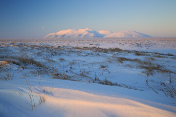 Winter arctic landscape. View of the snow-covered tundra and hills. Cold winter weather. Harsh...