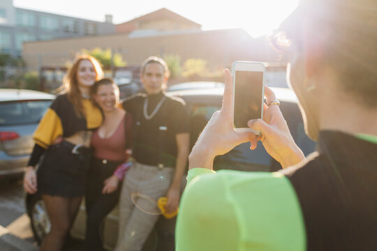 Man photographing friends through mobile phone on sunny day