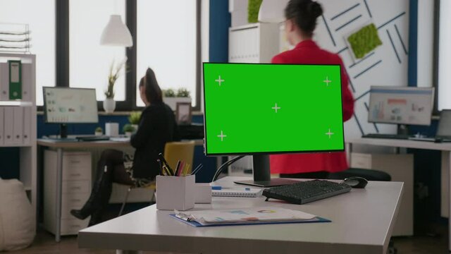 Close up of horizontal green screen on computer in business office. Isolated chroma key with blank mock up background and copy space template on monitor display at empty desk in space.