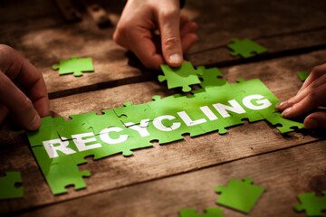 Friends joining recycling puzzle pieces on table