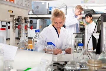 Portrait of European female scientist working with her colleagues in biochemical laboratory